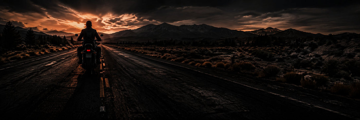 Motorcycle rider on an open desert road at sunset